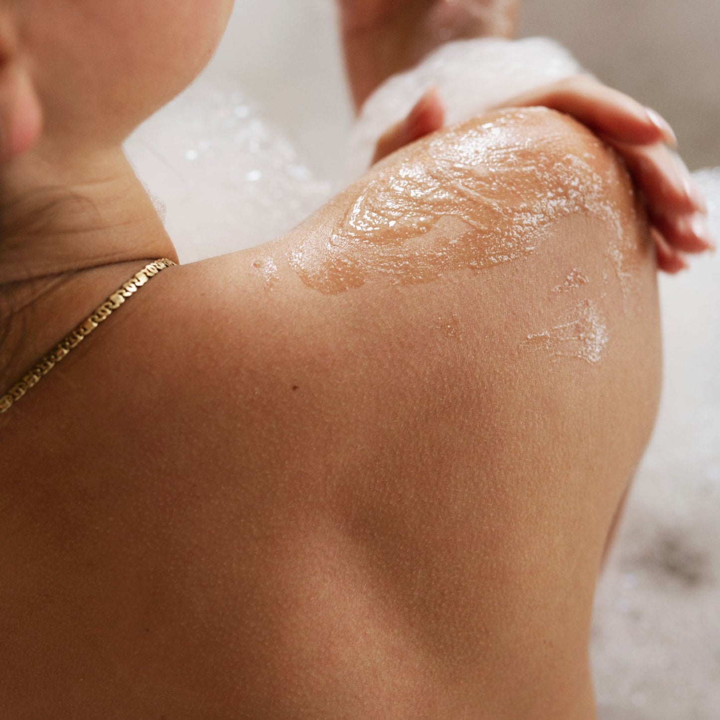 Lady using Wash & Scrub on shoulder in bath