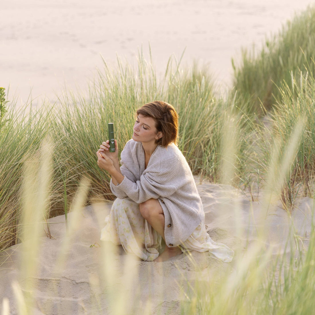 Lynn Van Royen on the beach holding the moisturiser for dry skin