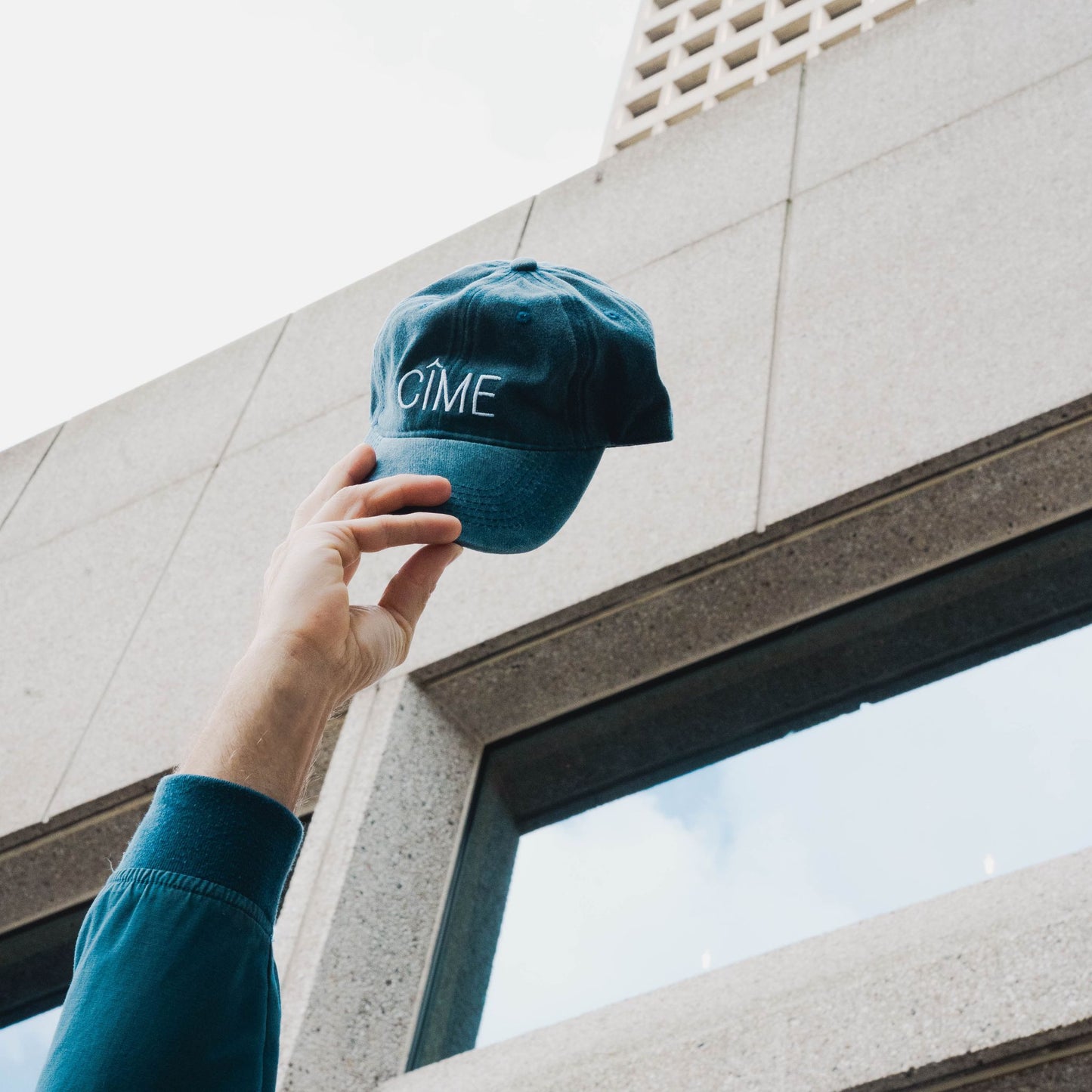 Person holding CÎME cap